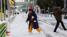 Une Japonaise marche avec des bâtons dans les rues de Tokyo recouvertes d'un épais manteau blanc, le 9 février.