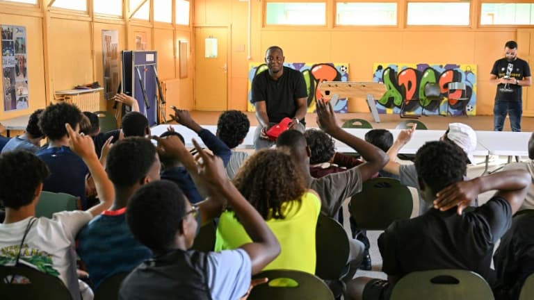 L'ex-détenu Adama Camara s'entretient avec des écoliers après une visite de sa "Grotte Mobile", un camion où il a reconstitué son ancienne cellule pour "sensibiliser" les jeunes à la vie en prison, le 11 juin 2025 à Drancy, en Seine-Saint-Denis