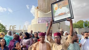 Des partisans du président nigérien Mohamed Bazoum, portant un portrait du président, se rassemblent pour lui manifester leur soutien, à Niamey le 26 juillet 2023.