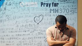 Un homme devant un tableau de soutien aux victimes du vol MH370 à Pékin, le 23 avril 2014.