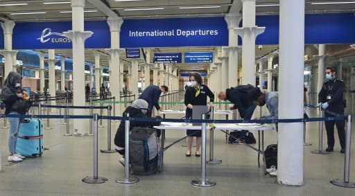 Des voyageurs équipés de masques de protection remplissent un formulaire au terminal de l'Eurostar de St Pancras, le 8 juin 2020 à Londres Des voyageurs équipés de masques de protection remplissent un formulaire au terminal de l'Eurostar de St Pancras, le 8 juin 2020 à Londres