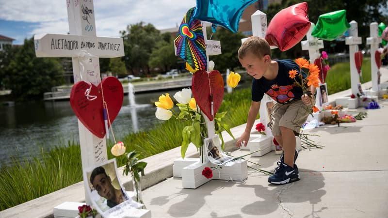 Un enfant dépose des fleurs au pied de chacune des croix érigées en hommage au 49 victimes de la fusillade du Pulse d'Orlando, le 17 juin 2016 à Orlando, Floride.