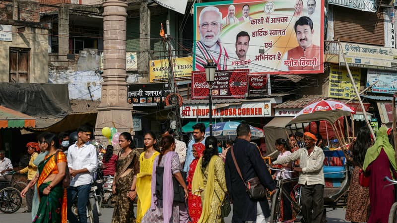 Des passants devant une affiche électorale du Bhaaratiya Janata Party (BJP) de Narendra Modi à Varanasi, dans l'État de l'Uttar Pradesh, ce samedi 16 mars. 