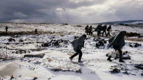Des migrants traversent des champs enneigés après avoir traversé la frontière macédonienne avec la Serbie, près du village de Miratovac, le 18 janvier 2016