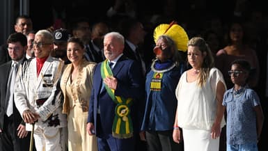 Lula reçoit son écharpe présidentielle lors de son investiture des mains d'un groupe de citoyens, dont le chef Raoni Metuktire, à Brasilia le 1er janvier 2023