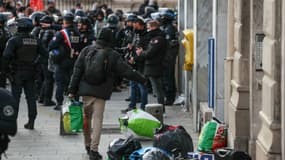 Un homme portant un sac contenant ses affaires se dirige vers des CRS qui montent la garde à la Gaîté Lyrique, une salle de spectacle parisienne occupée depuis trois mois par 450 jeunes migrants, suite à un ordre de police de quitter les lieux à Paris le 18 mars 2025.