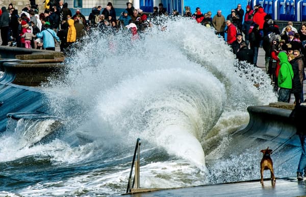 Des personnes se rassemblent pour regarder les vagues se briser sur la digue à Wimereux, dans le nord de la France, le 21 mars 2015.