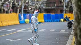 Un employé en tenue de protection dans une rue d'une quartier confiné de Shanghai, le 31 mars 2022 en Chine