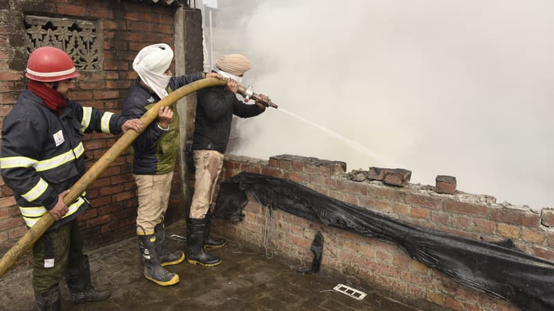 Deux pompiers tentent d'éteindre un incendie à Amritsar, en Inde.