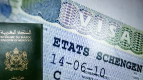 Une photo prise le 28 septembre 2021 dans la capitale marocaine Rabat montre un passeport marocain adossé à un visa Schengen. Paris va fortement réduire le nombre de visas accordés aux personnes originaires d'Algérie, du Maroc et de Tunisie.