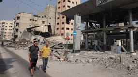 Des hommes passent devant une station essence détruite à Gaza City, dans la bande de Gaza, le 28 octobre 2023