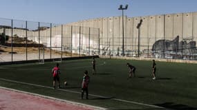 Des garçons palestiniens jouent au football le long du mur de séparation dans le camp de réfugiés d'Aida, à l'extérieur de Beit Jala, en Cisjordanie occupée, le 9 mai 2025. 