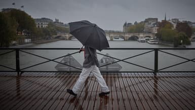 Une personne s'abrite sous un parapluie en traversant le pont des Arts durant la dépression Kirk qui provoque de fortes pluies sur le centre de Paris, le 9 octobre 2024.