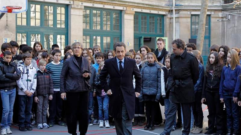 Nicolas Sarkozy (au centre), entouré du ministre de l'Education nationale Luc Chatel (à droite) et de la directrice du collège François Couperin, à Paris, après une minute de silence pour rendre hommage aux victimes de la tuerie de Toulouse, qui ajoutée à