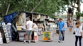 Des personnes devant des étals de bouquinistes à Paris le 2 août 2011