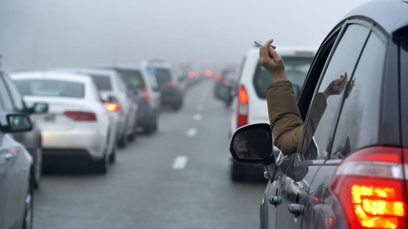 Un automobiliste fume une cigarette à la fenêtre de sa voiture (Photo d'illustration)