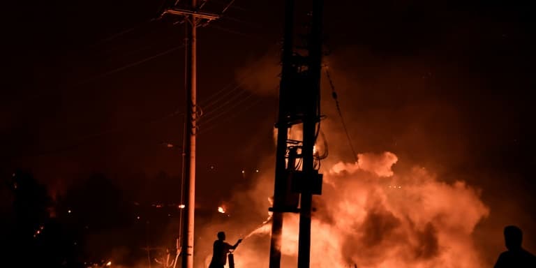 Un homme utilise un extincteur pour tenter de lutter contre un incendie de forêt à Dekelia (Grèce), au nord d'Athènes, le 3 août 2021