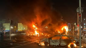 Des flammes s'élèvent de la voiture et d'un bus incendiés à la jonction de Bachelors Walk et du pont O'Connell, à Dublin le 23 novembre 2023, alors que les gens descendaient dans la rue après les agressions au couteau plus tôt dans la journée. Des manifestants à Dublin ont incendié jeudi une voiture et se sont battus avec la police, a rapporté un journaliste de l'AFP, après que trois enfants ont été blessés lors d'une attaque présumée à l'arme blanche dans une école, que les rumeurs sur les réseaux sociaux attribuaient à un ressortissant étranger.
