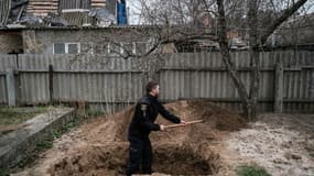 Le policier ukrainien Bogdan Demtsiura exhume le corps d'Andriy Samforskyi, mort à l'âge de 87 ans de maladie le 26 mars 2022 et enterré provisoirement dans son jardin à cause de la guerre, le 19 avril 2022 à Boutcha (Ukraine)