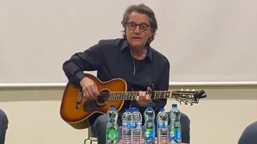 Francis Cabrel joue de la guitare devant les joueurs de XV de France à Marcoussis.