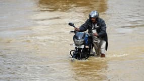 Un habitant de Colombo poussant péniblement sa moto dans l'eau, le 26 mai 2017