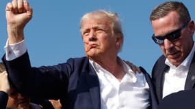 Donald Trump levant le poing en étant évacué d'un meeting de campagne après avoir été visé par des tirs, le 13 juillet 2024.