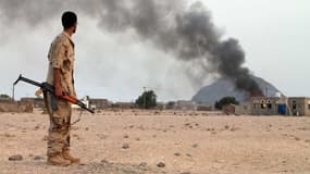Un combattant yéménite du Comité de résistance populaire observe de la fumée s'élevant d'un bâtiment après un raid aérien.