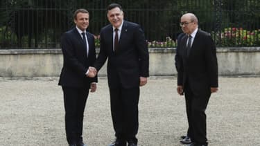 Le président Emmanuel Macron et le chef du gouvernement de Tripoli Fayyez al-Sarraj se serrent la main, accompagnés du ministre français des Affaires étrangères Jean-Yves Le Drian, à La Celle-Saint-Cloud, près de Paris, le 25 juillet 2017