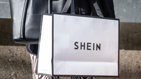 Une femme tient un stand de sacs Shein devant le premier showroom permanent du géant chinois de la mode rapide en ligne Shein le jour de l'ouverture de la boutique à Tokyo, le 13 novembre 2022.