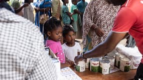 Une jeune fille regarde les habitants recevoir de la nourriture et de l'eau lors d'une distribution dans la ville de Mtsahara, sur le territoire français de Mayotte dans l'océan Indien, le 25 décembre 2024. 