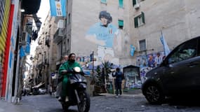 Un scooter passe devant une fresque représentant la légende du football argentin Diego Maradona dans les "quartiers espagnols" de Naples, le 23 novembre 2021