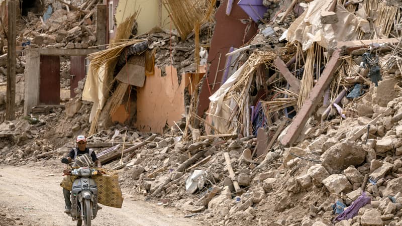 Un homme conduit sa moto à côté des décombres dans le village d'Imi N'Tala, au centre du Maroc, le 5 octobre 2023.