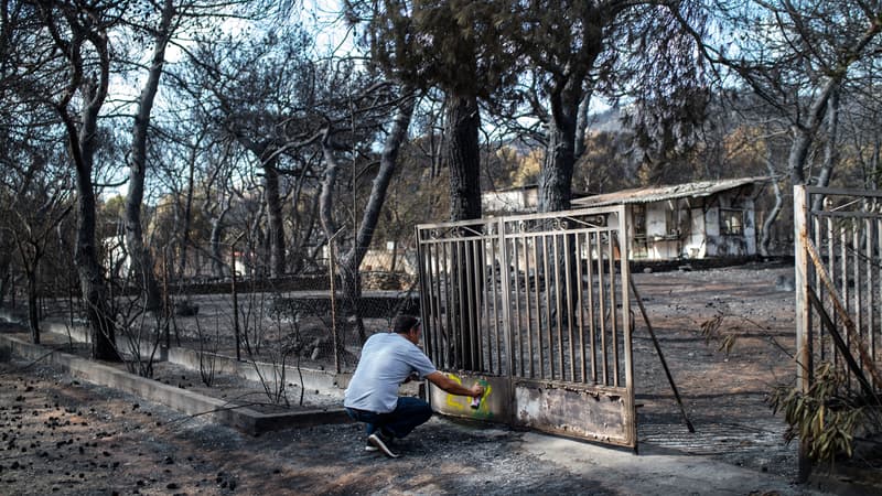 Un expert marque le portail d'une maison brûlée dans le village de Neos Voutzas, près d'Athènes le 26 juillet 2018.