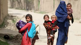 Une femme afghane marchant avec des enfants dans le district d'Argo en Afghanistan, le 13 avril 2023.