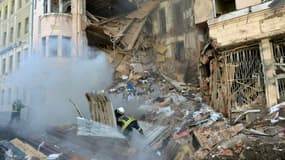 Des pompiers s'affairent auprès d'un immeuble éventré par une frappe russe à Kharkiv, dans l'est de l'Ukraine, le 14 mars 2022