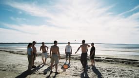 Un groupe d'amis en train de jouer sur une plage ensoleillée.