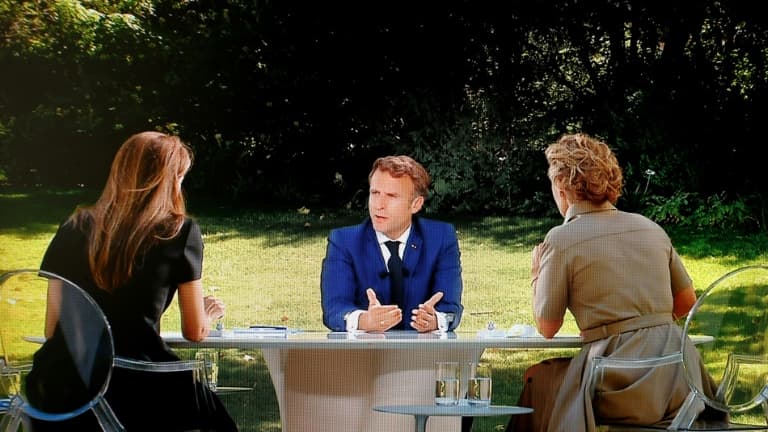 Photo d'un écran télé montrant le président Emmanuel Macron répondant aux questions des journalistes Anne-Claire Coudray (G) et Caroline Roux (D) le 14 juillet 2022 au palais de l'Elysée à Paris