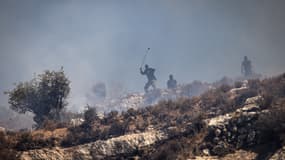 Des colons israéliens masqués lancent des pierres sur des Palestiniens depuis le sommet d'une colline dans le village de Sinjil, en Cisjordanie occupée, le 4 juillet 2025