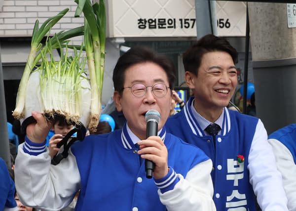 Le leader du principal parti d'opposition sud-coréen Lee Jae-myung brandit des oignons verts le 5 avril 2024 lors d'un événement de campagne pour les législatives. 