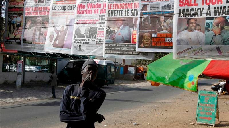 Devant le stand d'un vendeur de journaux à Dakar, lundi. Les résultats du premier tour de l'élection présidentielle disputé dimanche au Sénégal s'annoncent très serrés entre le président sortant Abdoulaye Wade et l'ancien Premier ministre Macky Sall, selo