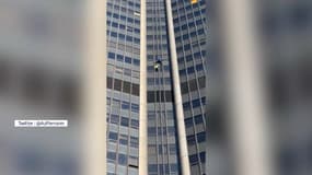 Deux grimpeurs vêtus des couleurs de l'Ukraine escaladent la tour Montparnasse à Paris, le 7 mars 2022.