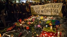 Des personnes rassemblées place de la Bourse à Bruxelles, le 22 mars 2016, devant un parterre de bougies, de fleurs et de messages en hommage aux victimes des attentats