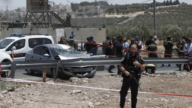 Un soldat israélien sur les lieux de l'attaque à la voiture pigée, près de la colonie de Teoka, dans le sud de Jérusalem le 10 juillet 2017.