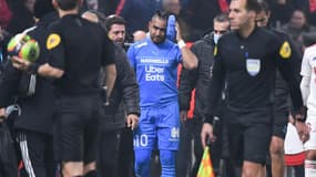 Le capitaine de l'OM Dimitri Payet quitte la pelouse après avoir été touché à la tempe par une bouteille lancée depuis une tribune de supporters lyonnais au Parc OL, le 21 novembre 2021 