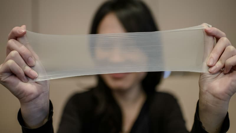 Une femme tire sur l'un des échantillons du plus mince préservatif en latex du monde lors d'une conférence de presse à Hong Kong, le 20 février 2014. Les préservatifs fabriqués par la société chinoise Guangzhou Daming United Rubber Products.