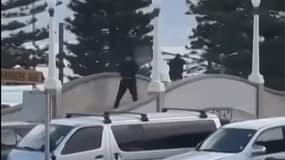 Cette capture d'écran tirée d'une vidéo fournie par UGC, gracieusement mise à disposition de l'AFP par Timothy Brant-Coles, montre deux hommes armés vêtus de noir tirant plusieurs coups de feu sur un pont à Bondi Beach, à Sydney, le 14 décembre 2025.