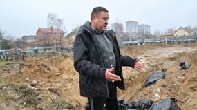Un homme se tient devant une fosse commune de la ville ukrainienne de Boutcha, près de Kiev, le 3 avril 2022