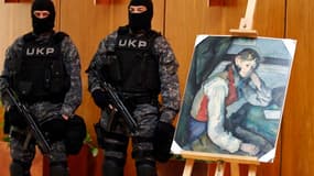 Membres des forces spéciales serbes surveillant à Belgrade une célèbre toile de Paul Cézanne, "Le Garçon au gilet rouge". Cette peinture, qui avait été dérobée il y a quatre ans dans une galerie en Suisse, a été retrouvée par la police serbe. /Photo prise