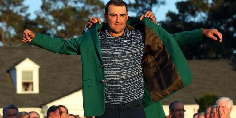 Le numéro un mondial, l'Américain Scottie Scheffler, vainqueur du Masters, enfile la traditionnelle veste verte, remise par le précédent vainqueur, le Japonais Hideki Matsuyama, le 10 avril 2022 à Augusta (Géorgie