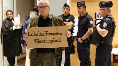 Un homme tient une pancarte où est écrit "La justice française, 13 ans trop tard" au tribunal où se déroule le procès du crash du Rio-Paris, le 10 octobre 2022 à Paris